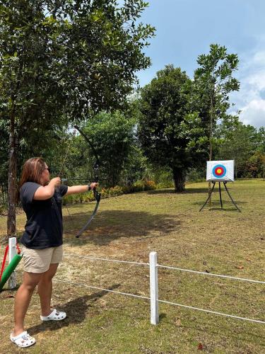a woman is swinging a bat at a target at "D'BAMBOO KAMP" Desa Wisata Ekang in Lagoi