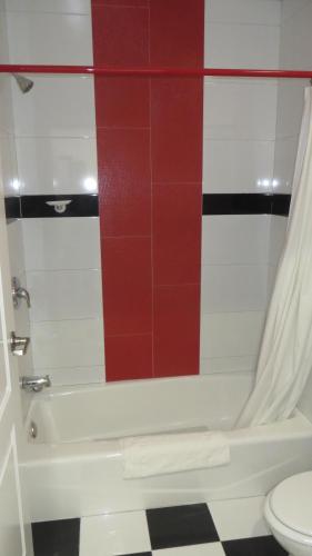 a bathroom with a white tub and a red tile wall at Legend Hotel Hollywood in Los Angeles