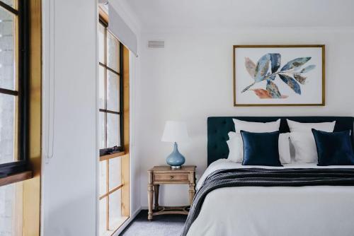 a bedroom with a bed with blue and white pillows at Park Crescent - Daylesford Macedon Region in Kyneton