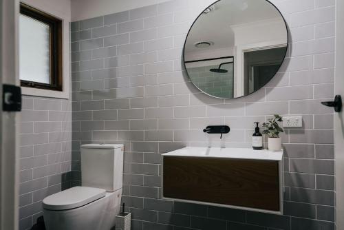 a bathroom with a toilet and a sink and a mirror at Park Crescent - Daylesford Macedon Region in Kyneton