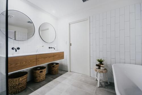a bathroom with a tub and a sink and mirrors at Park Crescent - Daylesford Macedon Region in Kyneton