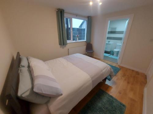 Schlafzimmer mit einem Bett mit weißer Bettwäsche und einem Fenster in der Unterkunft West coast countryside escape in Tuam