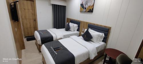 a hotel room with two beds and a television at Hotel Shayan Inn in Rajkot