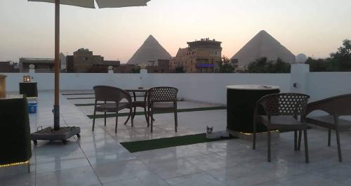 a patio with chairs and a table with pyramids in the background at Matto Pyramids Inn in Cairo