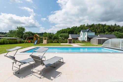 a swimming pool with two chairs and a swing at Holiday House Adam in Prosečné
