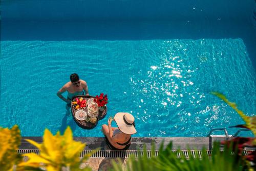 un hombre en el agua con un tazón de comida en una piscina en The Oriental Jade Hotel en Hanói