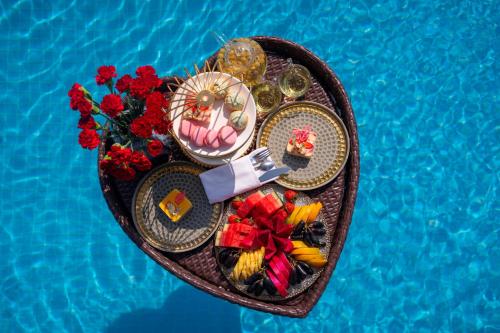 a heart shaped tray with food and flowers next to a pool at The Oriental Jade Hotel in Hanoi