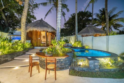 a patio with a table and a swimming pool at The Cove Gili Air in Gili Islands