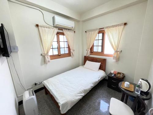 a bedroom with a bed and a tv and windows at 芹壁山城民宿 Chinbe Hill Village House B&B in Beigan