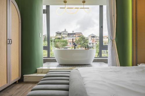 大叻的住宿－The Palette Dalat，一间带浴缸和大窗户的卧室