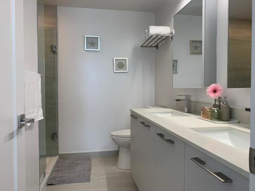 La salle de bains blanche est pourvue de 2 lavabos et de toilettes. dans l'établissement QQ MARKHAM condo, à Markham