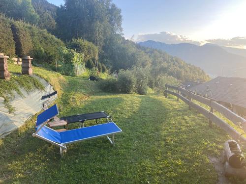 un banco azul sentado en el césped en una colina en Nostalgie di un tempo nelle Dolomiti, en Pergine Valsugana