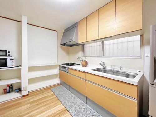 a kitchen with wooden cabinets and a sink at 令康民泊八尾 in Higashi-osaka