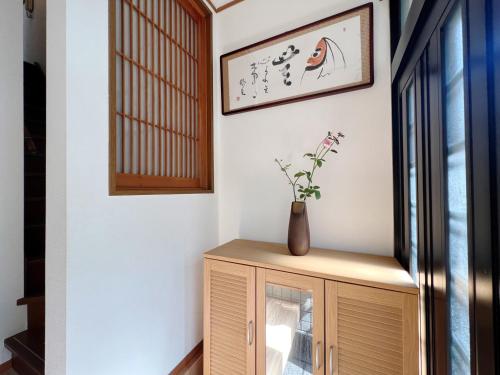 a room with a cabinet with a vase on it at 令康民泊八尾 in Higashi-osaka