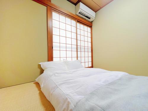 a white bed in a room with a window at 令康民泊八尾 in Higashi-osaka