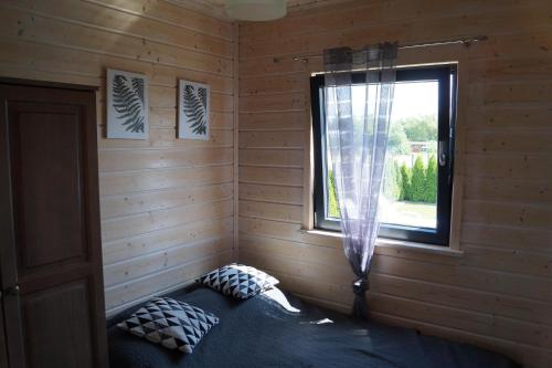 - une chambre avec un lit dans une cabane en rondins dotée d'une fenêtre dans l'établissement SŁONECZNE DOMKI, à Gąski