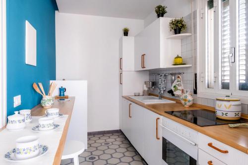a kitchen with white cabinets and blue walls at Casa Duca - Marina di Ragusa in Marina di Ragusa