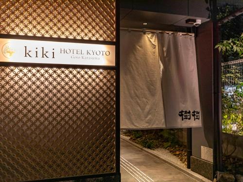 a sign for a hotel koko next to a fence at Tabist kiki HOTEL KYOTO Gojo Karasuma in Nishinotōindōri