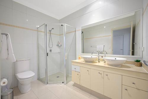 a bathroom with two sinks and a shower and a toilet at Marsfield New Modern Townhouse in Sydney