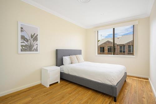 a white bedroom with a bed and a window at Marsfield New Modern Townhouse in Sydney