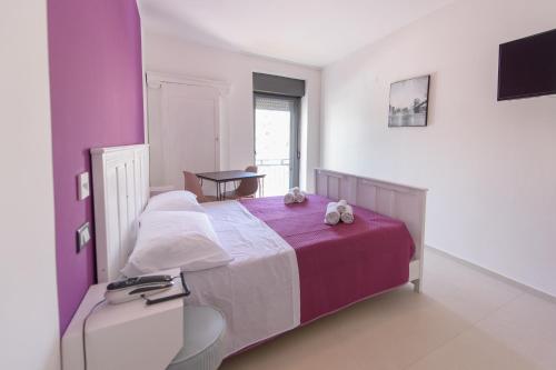 a bedroom with a purple and white bed and a table at Al Rayyan - Affittacamere in Montesano Salentino