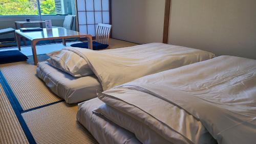 two beds sitting in a room with a table at Ito Yukitei in Ito