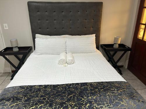 ein Bett mit zwei weißen Handtüchern darauf mit zwei Tischen in der Unterkunft Home away from Home in East London