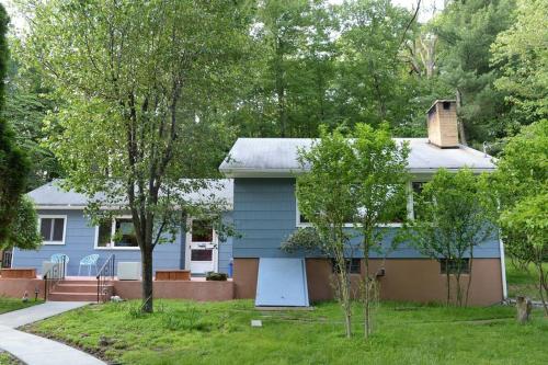 a blue house with trees in front of it at 3 Acre Lake Paradise Swimming Pool & Jacuzzi HotTub! in Hopatcong