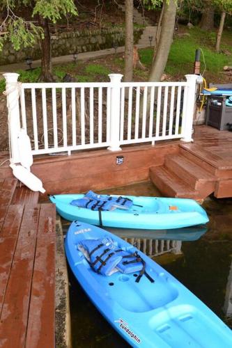 three kayaks sitting on a dock with a white fence at 3 Acre Lake Paradise Swimming Pool & Jacuzzi HotTub! in Hopatcong