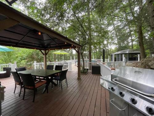 a wooden deck with a table and chairs and a grill at 3 Acre Lake Paradise Swimming Pool & Jacuzzi HotTub! in Hopatcong