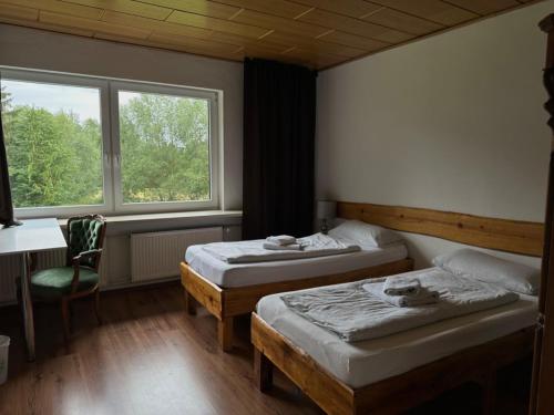 1 dormitorio con 2 camas, escritorio y ventana en Alte Ranch, en Seesen