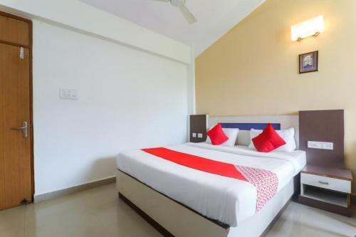 a bedroom with a large white bed with red pillows at Hotel City Garden in Madgaon