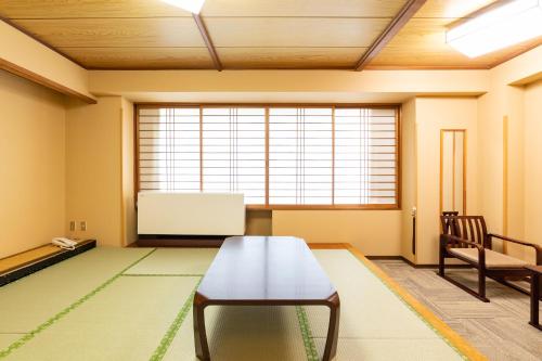 a room with a table and a chair and a window at Ooedo Onsen Monogatari Kounkaku in Osaki