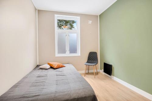a bedroom with a bed and a chair and a window at Illevollen in Trondheim