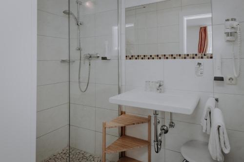 uma casa de banho branca com um lavatório e um chuveiro em Sporthotel Kitz em Bruck an der Grossglocknerstrasse
