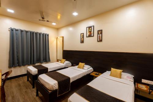 una camera con tre letti di Hotel Ellora Park a Pune
