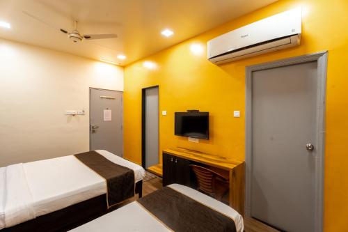 a hotel room with two beds and a tv at Hotel Ellora Park in Pune