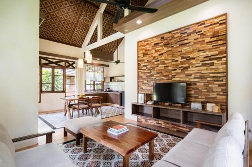Mutiara Carita Cottages في كاريتا: غرفة معيشة مع جدار من الطوب وتلفزيون