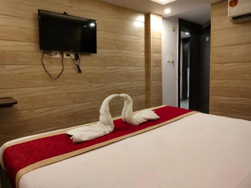 twee witte zwanen op een bed in een slaapkamer bij Kanha Inn Sultanpur Road in Lucknow