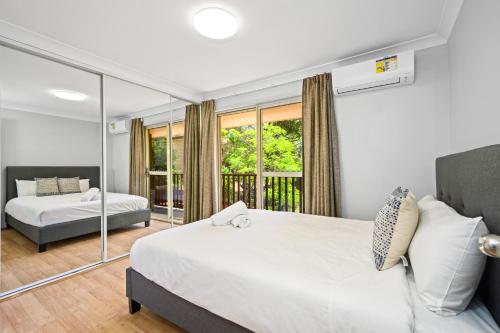 1 Schlafzimmer mit 2 Betten und einem Balkon in der Unterkunft Marsfield 5 bed Townhouse near Macquarie Uni FreeP in Sydney