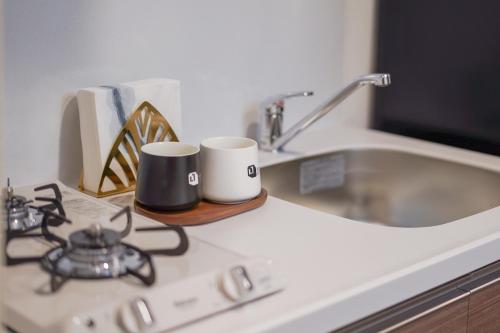 a stove top with two coffee cups on a counter at Apartment Hotel 11 Namba-Minami Ebisucho-Eki Mae in Osaka