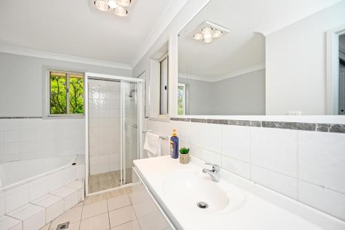 ein weißes Bad mit einem Waschbecken und einer Dusche in der Unterkunft Marsfield 5 bed Townhouse near Macquarie Uni FreeP in Sydney