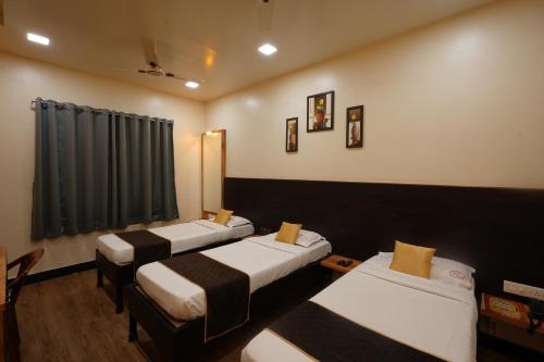 a room with four beds in a row with a window at Hotel Ellora Park in Pune