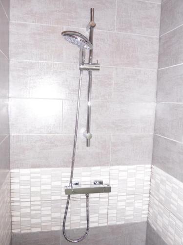une douche avec pommeau de douche dans une salle de bain dans l'établissement Cottages de la ville Daniou, à Langrolay