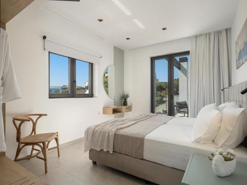 a white bedroom with a bed and a chair at Avrilia Seaside Villa HEATED POOL in Almyrida