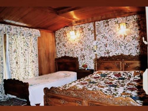 Un dormitorio con dos camas y papel pintado floral. en Iram Houseboats, en Srinagar
