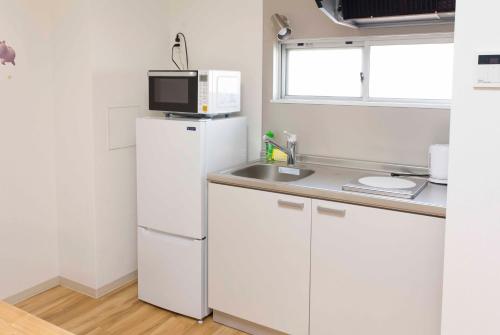 a kitchen with a white refrigerator and a microwave at PAL-TERRACE Fujimi in Tokyo