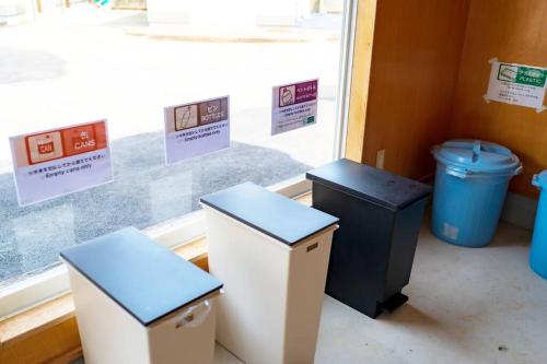 three trash cans sitting next to a window at 日向サーフキャンプ111 in Hyuga