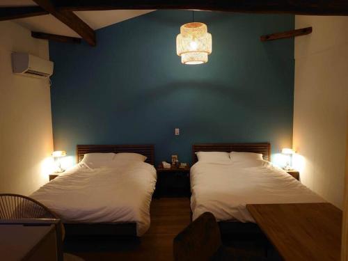 a bedroom with two beds and a blue wall at 日向サーフキャンプ111 in Hyuga