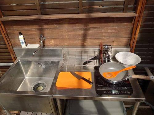 a kitchen sink with a pan and utensils on it at 日向サーフキャンプ111 in Hyuga